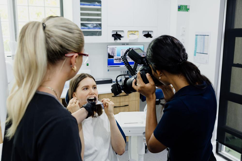 A woman photographs another woman undergoing a full mouth reconstruction in a dental chair at Northside Dental Solutions Clayfield.