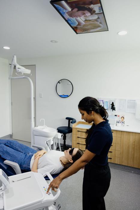 A woman sits in a dental chair while a dentist stands beside her, preparing for a tooth extraction at Northside Dental Solutions.