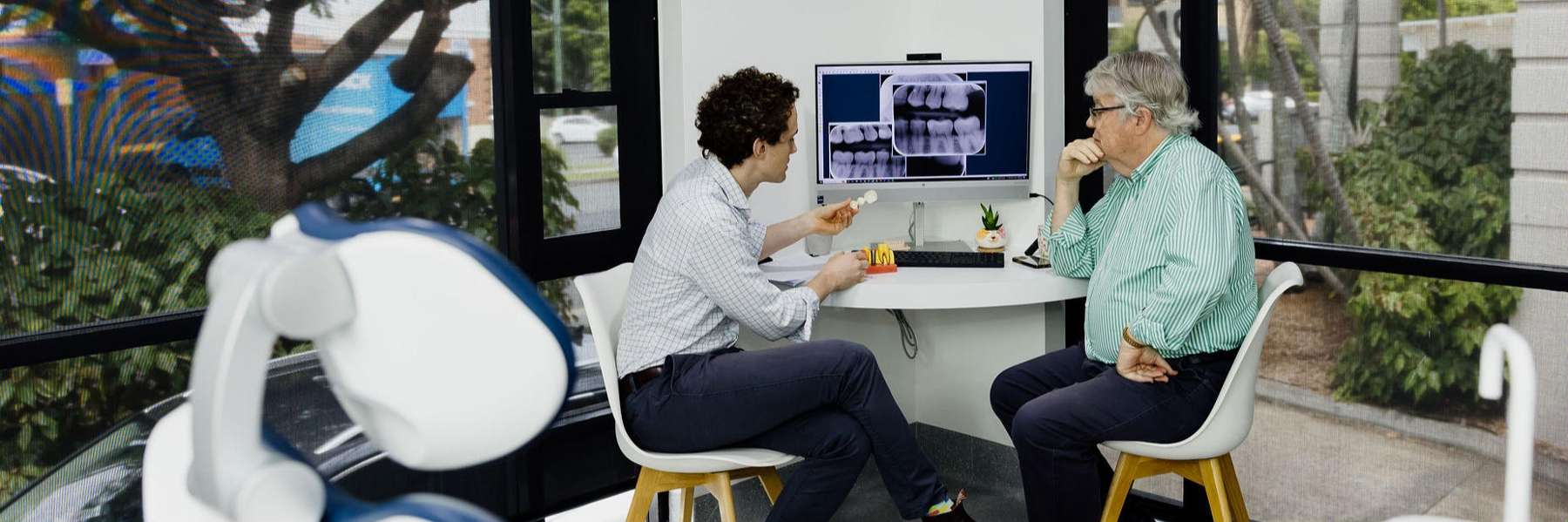 Two individuals at a table with a computer, collaborating in a general dentistry setting in Clayfield.