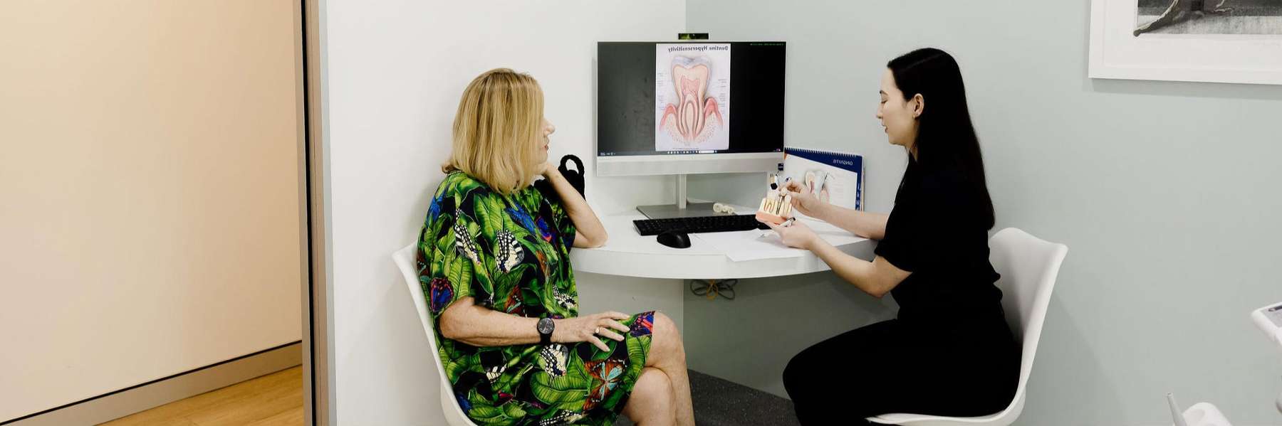 Two women seated at a desk in a dental office, discussing root canal treatment at Northside Dental Solutions Clayfield.